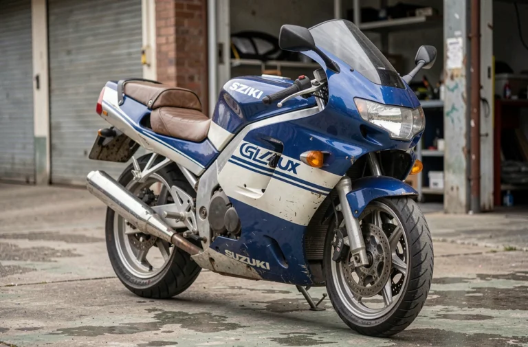 Suzuki GSXR 1100 en livrée bleue et blanche des années 90 garée dans un garage urbain, vue en angle 3/4 avant avec détails chromés et patine authentique